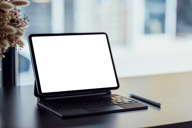 Close-up van de digitale tablet leeg scherm met kantoorbenodigdheden op zwarte houten tafel.