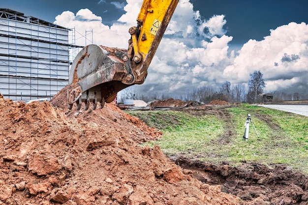 Close-up van de graafbak op de bouwplaats De graafmachine graaft een greppel voor ondergrondse nutsvoorzieningen Bouwmateriaal voor grondwerken