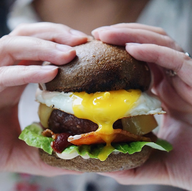 Close-up van de hand die de burger op het bord houdt