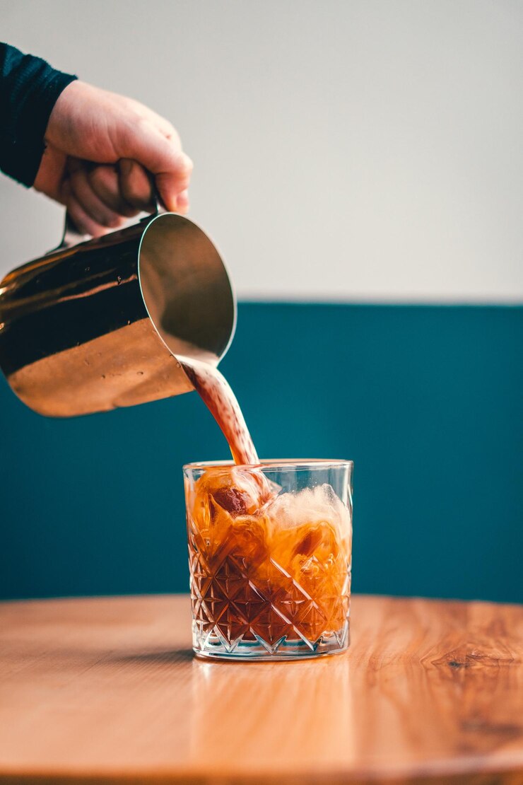 Foto close-up van de hand die drank in een glas op tafel giet