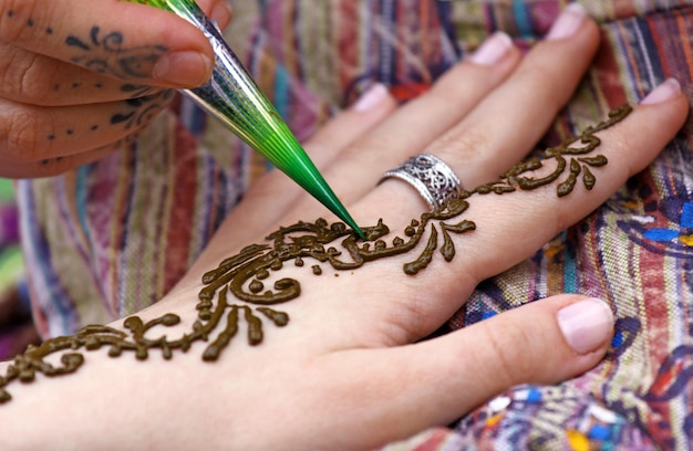 Foto close-up van de hand die een henna-tattoo krijgt