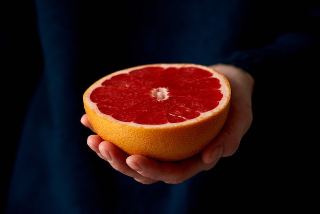 Close-up van de hand die van de vrouw verse gehalveerde rode heldere citrusvruchten grapefruit houdt