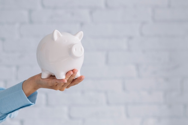 Foto close-up van de hand die van een persoon witte piggybank houdt