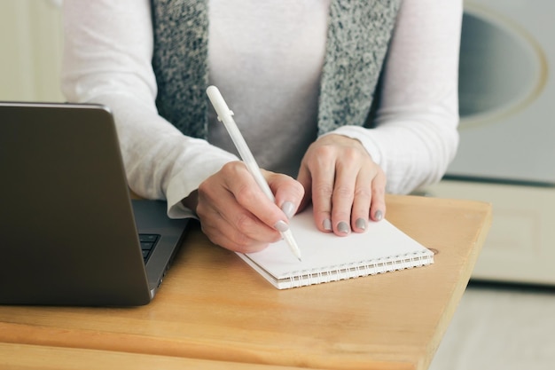 Close-up van de hand met pen om te schrijven op een leerboekbestand terwijl u vanuit huis werkt aan een zakelijk project