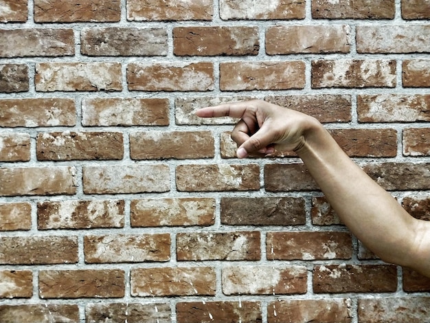 Foto close-up van de hand tegen de bakstenen muur