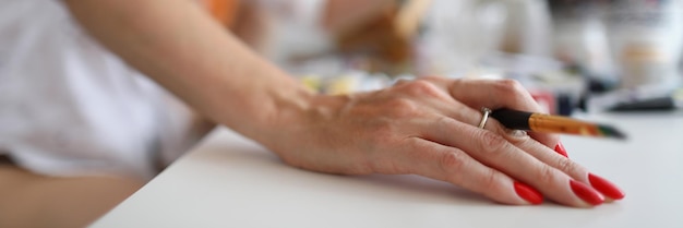 Close-up van de hand van de schildersdame met penseel roodharige vrouw die thuis een foto maakt