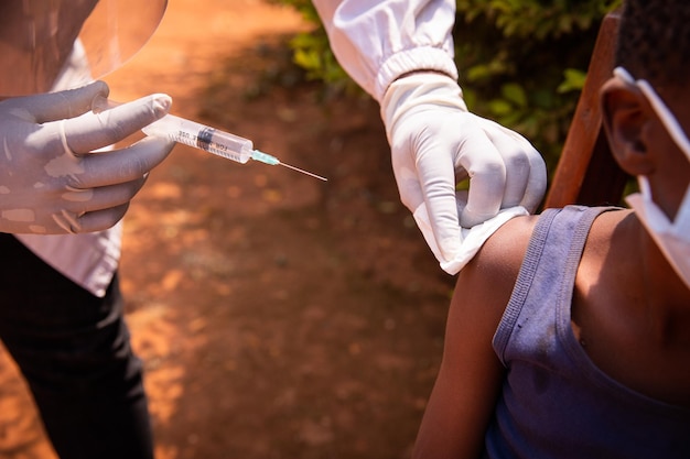 Close-up van de hand van een arts met een spuit die op het punt staat het vaccin te injecteren bij een kind in Afrika Vaccinatieconcept