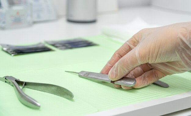 Close-up van de hand van een chiropodist die handschoenen draagt en een guts neemt van de werktafel