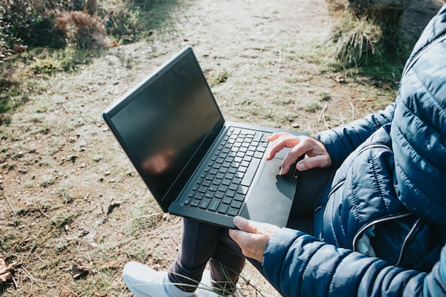 Close-up van de hand van een oude vrouw in de buitenlucht met behulp van een draagbare laptopcomputer om overal te werken en internet te gebruiken - technologieconcept. Oude mensen die buiten contact maken en delen