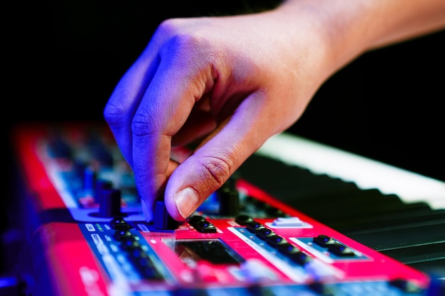 Close-up van de hand van een pianist die een elektronische synthesizer stemt