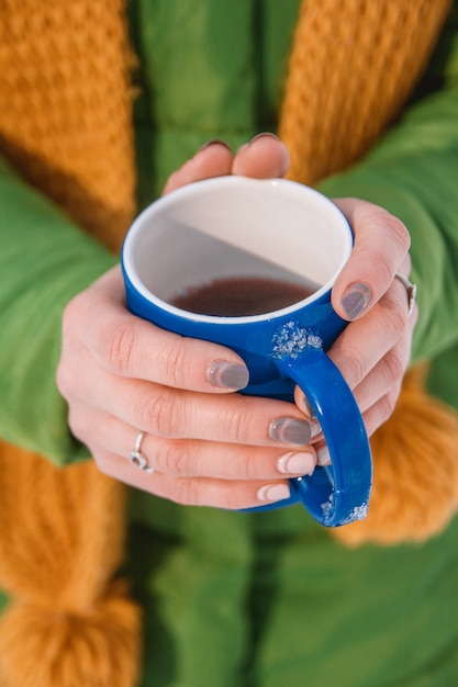 Close-up van de hand van een vrouw die een kop warme koffie vasthoudt.