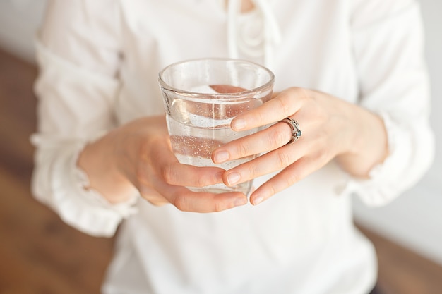 Close-up van de hand van een vrouw met een koud glas water en ijs