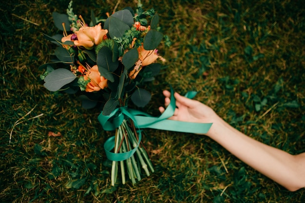 Foto close-up van de hand van het meisje en boeket van bloemen die op grond liggen