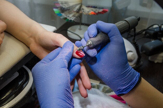 Close-up van de handen van de meester verwijdert de nagellak van de cliënt