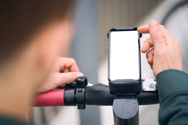 Close-up van de handen van de onbekende man met behulp van de mobiele telefoon terwijl de scooter is ontgrendeld