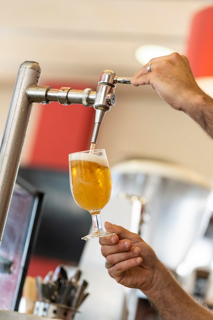 Close-up van de handen van een barman die een biertje bereidt met een bierdispenser