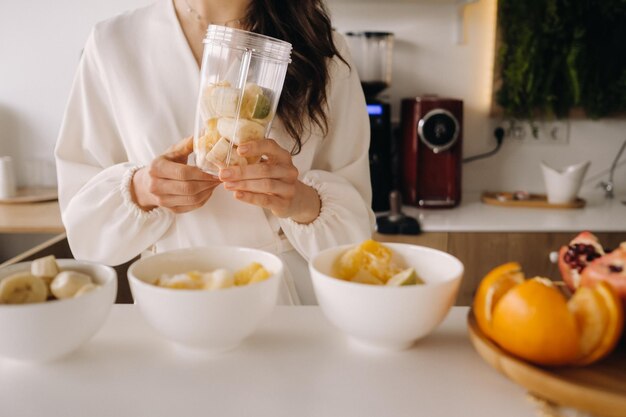 Close-up van de handen van een meisje dat een detoxcocktail van fruit maakt in de keuken Dieet voor gewichtsverlies