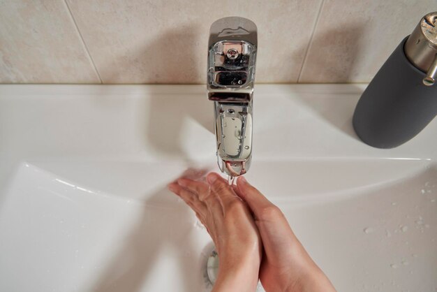 Close-up van de handen van een meisje dat ze wast in de badkamer