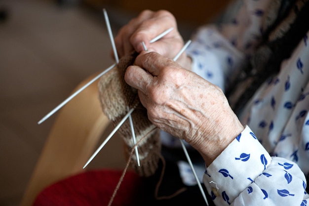 Close-up van de handen van een oudere vrouw die sok breit