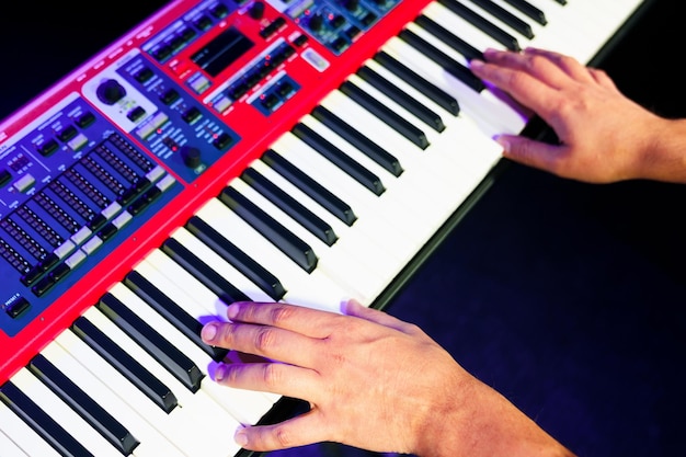 Close-up van de handen van een pianist op een elektronische synthesizer