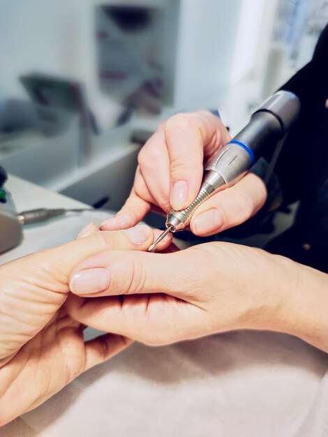 Close-up van de handen van een vrouw in een nagelsalon die een manicure krijgt