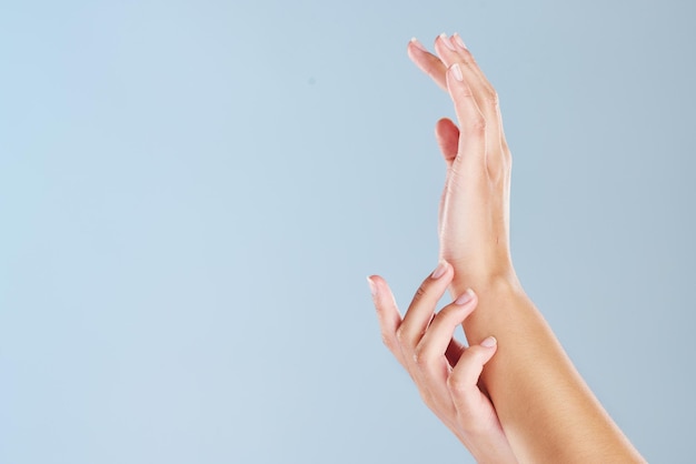 Close-up van de handen van een vrouw met een blauwe studio achtergrond en copyspace Zoom in op gemanicuurde vingernagels die zachte huid aanraken na gebruik van een schoonheidsbehandeling of huidmasker Handmodel met kopieerruimte