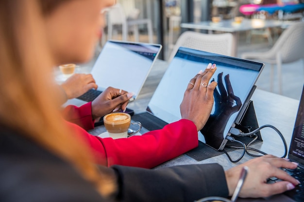 Close-up van de handen van zakenvrouwen die in een coworking-ruimte werken en koffie drinken