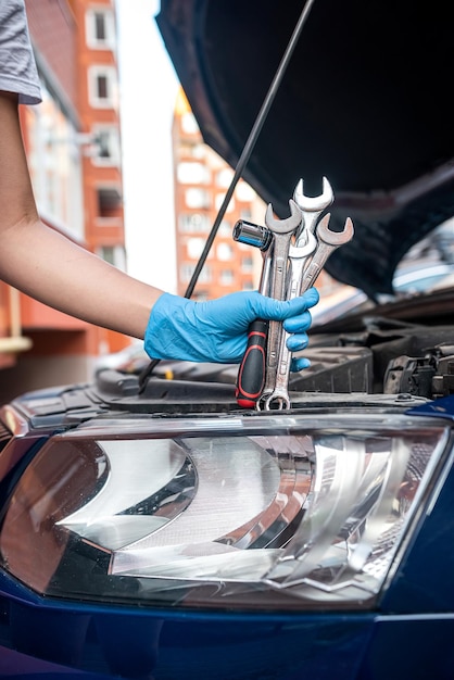 Close-up van de handsleutel van de automonteur om een onderdeel in de motorruimte van de auto te verwijderen