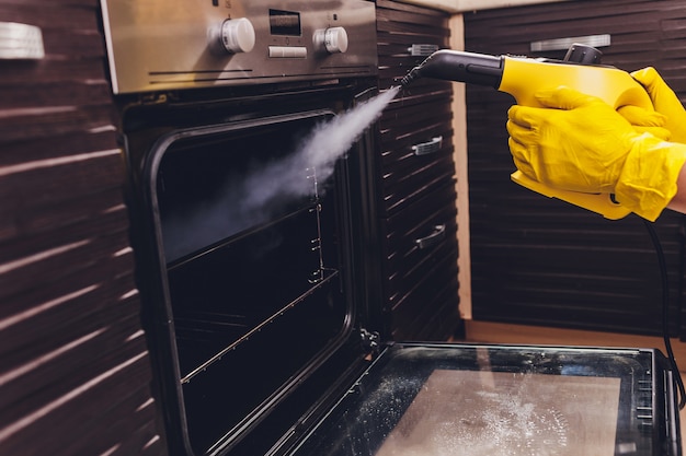 Close-up van de het huis het schoonmakende hand van de stoom schoonmakende oven.