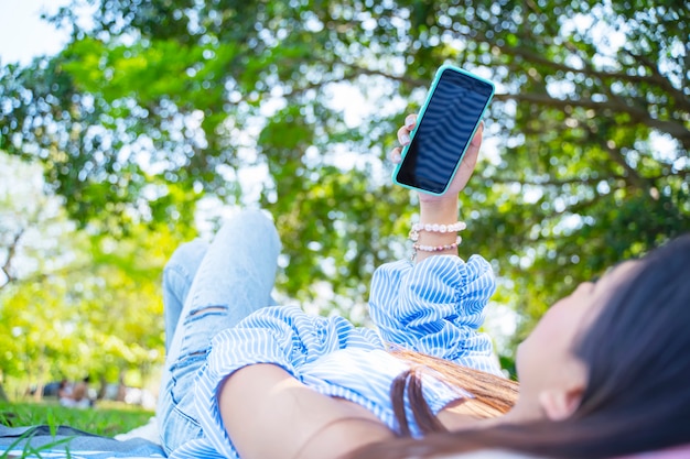 Close-up van de jonge vrouw op de grond liggen en het gebruik van mobiel met ontspannen.