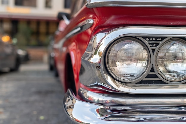 Close-up van de koplampen van een Amerikaanse retro auto met gekromde gepolijste delen rode carrosserie