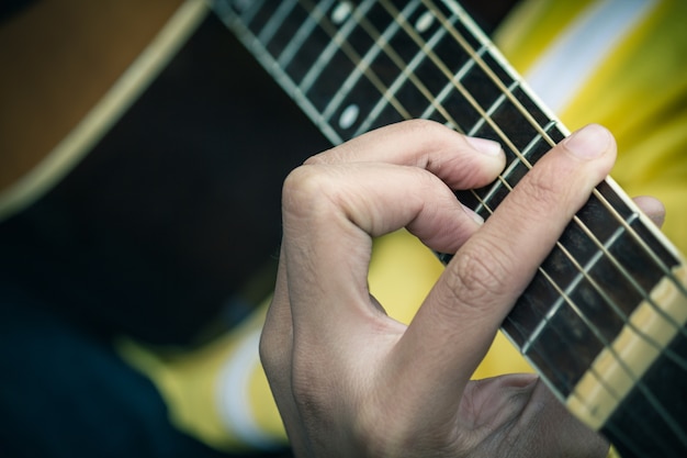 Foto close-up van de man handen spelen van akoestische gitaar, zachte vintage stijl