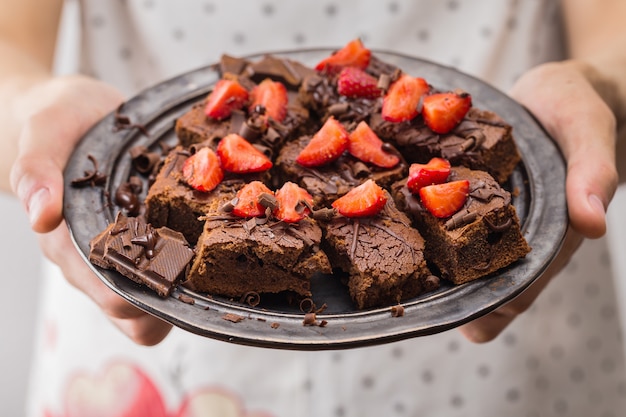 Foto close-up van de mens die klaar chocolade brownies houdt