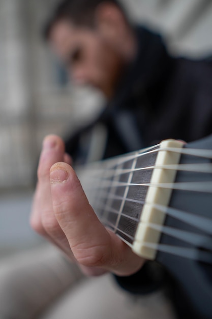 Close-up van de slecht verzorgde handen van een baarde man die alleen gitaar leert spelen