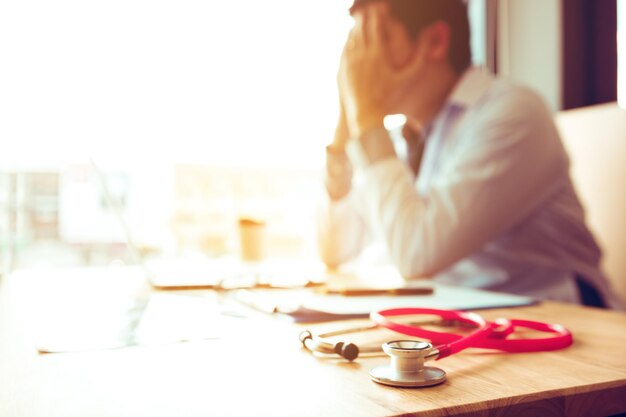 Close-up van de stethoscoop tegenover een gespannen mannelijke dokter aan het bureau.