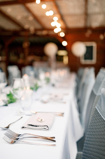 Close-up van de tafelvorken van een bruiloftsdiner op de voorgrond op een witte tafelkleedslinger over de?