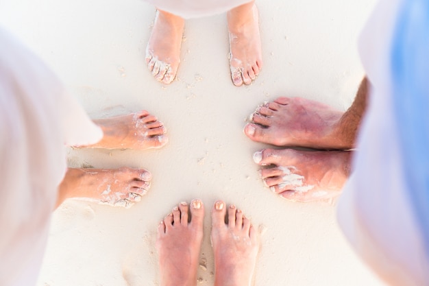 Close-up van de voeten van familie op het witte zandstrand