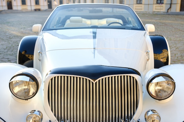 Close-up van de voorkant van een witte vintage auto op de binnenplaats van het kasteel.