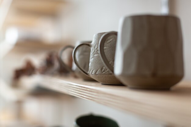 Close-up van designer keramische mokken handgemaakt op de plank. Aardewerk workshop.