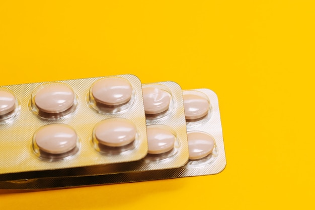Close-up van drie pakjes vitamines op een gele achtergrond. pillen in een verpakking