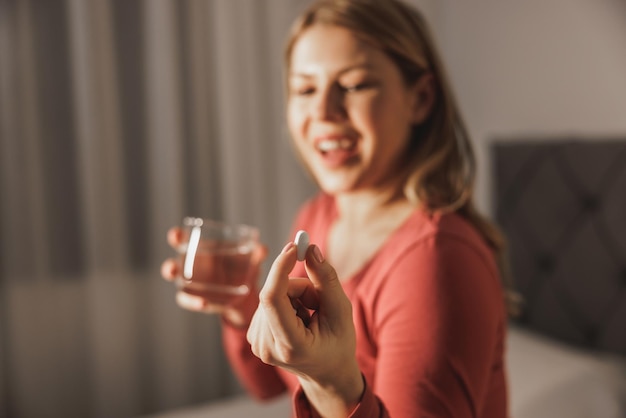 Close-up van een aanstaande vrouw die thuis een medicijn inneemt.