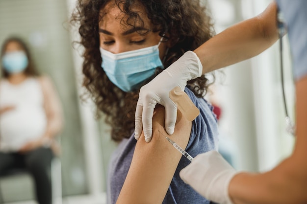 Close-up van een Afro-Amerikaans tienermeisje dat een vaccin krijgt vanwege een pandemie van het coronavirus.