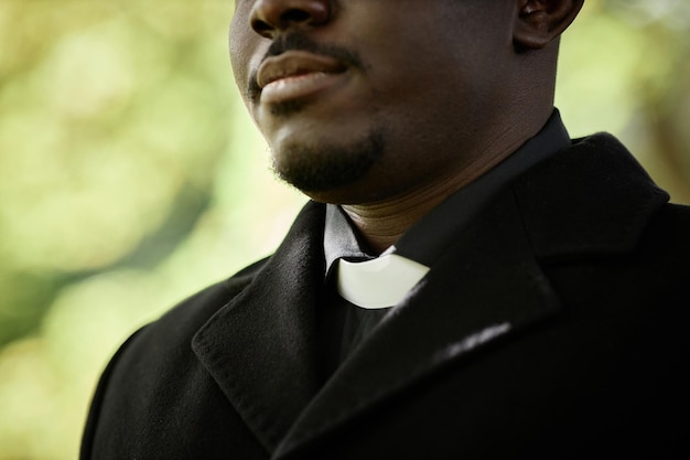 Close-up van een Afro-Amerikaanse priester die zwart draagt tijdens een begrafenisceremonie buiten met de nadruk op administratief