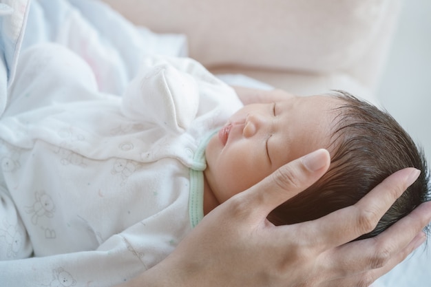 Close-up van een baby comfortabel slapen in de armen van de moeder