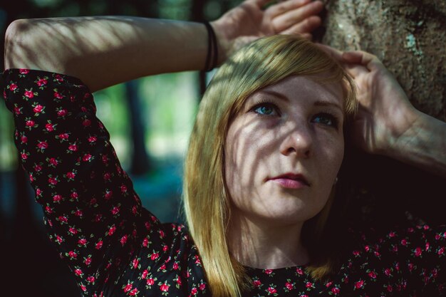 Foto close-up van een bedachtzame vrouw die bij een boom staat