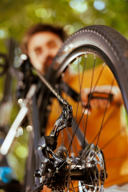 Close-up van een blanke man die fietsonderdelen repareert met een professioneel gereedschap in de achtertuin.