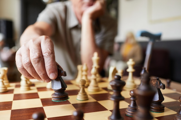 Close-up van een blanke senior man die schaak speelt en geniet van activiteiten in de kopieerruimte van een verpleeghuis