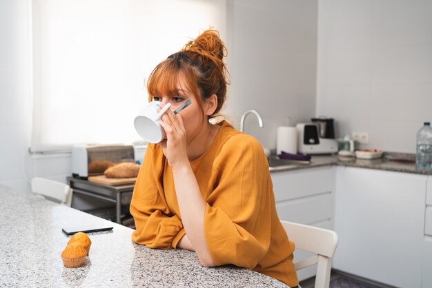 Close-up van een blanke vrouw die thee ontbijt in de keuken thuis