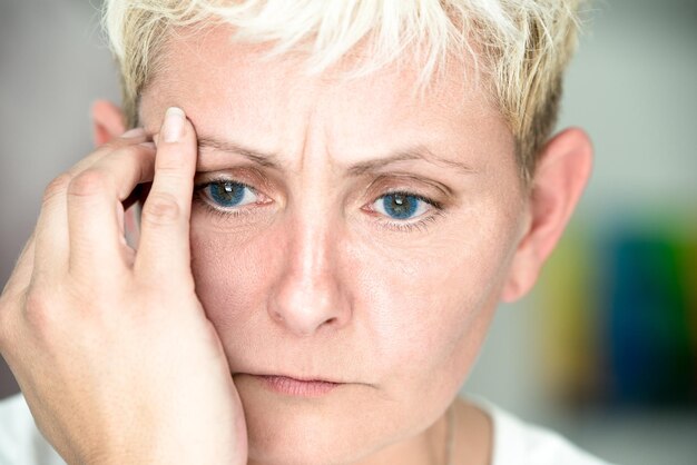 Foto close-up van een blonde vrouw met hoofdpijn.