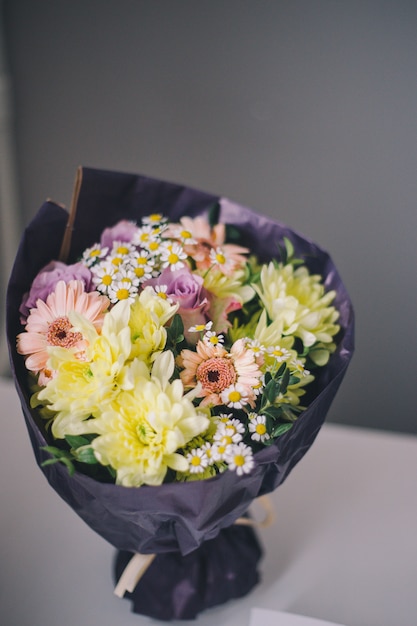 Close-up van een boeket van kleurrijke bloemen in paarse verpakkingsst